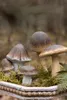 A decorative arrangement of ceramic mushrooms in a planter filled with moss and a fern. Produktbild-Vorschau