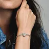 A close-up shot of a woman's wrist wearing a Pandora bracelet with a heart-shaped charm. Anteprima dell’immagine prodotto