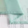 A close-up of a sheer green and white gradient curtain with text printed on it. Produktbild-Vorschau