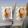 Two makeup mirrors with LED lights are shown on a white surface, with a woman's hands interacting with one of them. Produktbild-Vorschau