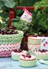Desserts and cherries are arranged on a blue wooden table outdoors, with plants and a red crate in the background. Produktbild-Vorschau
