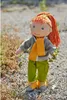 A doll standing outdoors on a gravel path with some vegetation. Produktbild-Vorschau