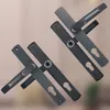 Two sets of door handles and lock mechanisms are displayed diagonally against a blurred background. Náhled obrázku produktu