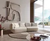 A modern living room with a large window overlooking a scenic landscape, featuring a cream-colored bouclé sofa.