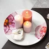 Three lit candles and a burnt matchstick on an oyster shell are placed on a decorative plate with floral patterns. Voir les images du produit