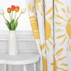 A close-up of a yellow sun-patterned curtain next to a white vase with tulips. Produktbild-Vorschau
