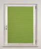 A green pleated blind is shown in a white window frame. Produktbild-Vorschau