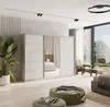 A modern bedroom with a large sliding door wardrobe, a bed, chairs, and ottomans, illuminated by natural light from a large window. Produktbild-Vorschau