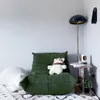 A cozy corner with a green sofa, a stuffed animal, a floor lamp, and a small side table. Voir les images du produit