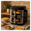 A kitchen counter scene featuring a dual-basket air fryer with food being cooked inside and prepared food on plates. Anteprima dell’immagine prodotto