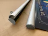Close-up view of two poster rails, one with a poster attached, on a brown surface. Produktbild-Vorschau