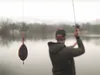 A person fishing by a lake on a foggy day. Produktbild-Vorschau