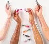 Multiple arms displaying swatches of lip oil in different shades against a white background. Podgląd zdjęcia produktu