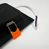 A close-up view of a black square LED light fixture with attached wires and a spring-loaded clip with an orange plastic cover. Anteprima dell’immagine prodotto