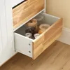 A close-up view of an open drawer in a white and wood sideboard, showing glass jars filled with food items. Produktbild-Vorschau