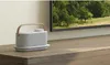 A portable speaker is placed on a wooden surface in front of a television. Anteprima dell’immagine prodotto