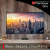 A television displaying a city skyline at sunset, with a small black satellite receiver on the wooden shelf below. Produktbild-Vorschau