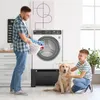 A father and son are doing laundry together with their dog in a bright, modern laundry room. Produktbild-Vorschau