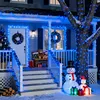 A decorated house porch with Christmas lights, wreaths, a Christmas tree, teddy bears, and inflatable snowmen. Náhled obrázku produktu