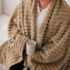 A person is holding a mug while wrapped in a plush blanket. Produktbild-Vorschau