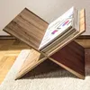 A wooden book stand holding an open book, placed on a rug. Voir les images du produit