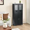 A black storage cabinet with glass doors and drawers is shown in a living room setting next to a sofa. Náhled obrázku produktu
