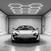 A silver McLaren sports car is parked in a modern garage with hexagonal ceiling lights. Voir les images du produit
