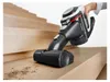 A hand is holding a black and white Bosch cordless vacuum cleaner and cleaning wooden stairs. Produktbild-Vorschau