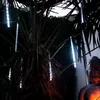 String lights hanging from a palm tree at night, with a Buddha statue in the foreground. Produktbild-Vorschau