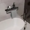 A bathroom shelf with toiletries and a towel hanging over a bathtub. Anteprima dell’immagine prodotto