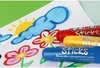 Three color sticks are placed on a drawing of a sun, clouds, and flowers. Voir les images du produit