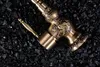 A close-up shot of a decorative bronze faucet resting on a bed of black stones. Podgląd zdjęcia produktu