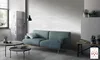 A modern living room with a blue sofa, coffee tables, and a brick-patterned wall. Náhled obrázku produktu