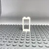 A single white LEGO window frame with a transparent pane, standing on a gray LEGO baseplate. Produktbild-Vorschau