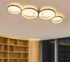 A modern ceiling light fixture with four circular rings, mounted on a ceiling above a bookshelf. Produktbild-Vorschau