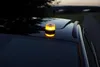 A yellow warning light is attached to the roof of a car at dusk. Produktbild-Vorschau