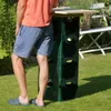 A person stands next to a DIY bar made of green beer crates and a wooden top in a garden. Produktbild-Vorschau