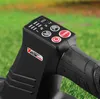 Close-up of the control panel of a black leaf blower, set against a blurred green grassy background. Produktbild-Vorschau