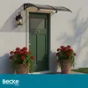 A green front door with a clear awning above it, flanked by two potted plants with red flowers. Náhled obrázku produktu