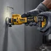 A person wearing gloves is using a DeWALT cordless drywall router to cut a hole in a wall. Podgląd zdjęcia produktu