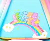A group of Care Bears sitting on a rainbow with clouds. Produktbild-Vorschau