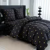 A bedroom scene with a bed dressed in black bedding with golden hearts. Produktbild-Vorschau