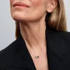 Close-up of a woman wearing a necklace with two heart-shaped pendants, one red and one white. Produktbild-Vorschau