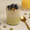 Glas mit Pistazien Overnight Oats geschichtet mit Chia Pudding, Topping aus Blaubeeren und Pistazien Produktbild-Vorschau