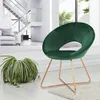 A dark green velvet chair with gold metal legs is placed in a modern living room with a staircase and a plant. Produktbild-Vorschau