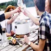 People toasting drinks around a table with a grill and food. Produktbild-Vorschau
