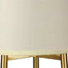 A close-up view of the bottom part of a lampshade and the gold-colored legs of a floor lamp. Podgląd zdjęcia produktu