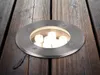 A round stainless steel ground light with multiple LED bulbs embedded in a wooden deck. Podgląd zdjęcia produktu