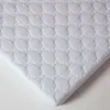 A close-up, angled view of a white quilted mattress protector. Anteprima dell’immagine prodotto