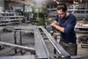 A man is using a drill in a workshop. Voir les images du produit